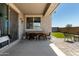 Covered patio with sleek outdoor dining set and an adjacent artificial lawn for easy backyard enjoyment at 17171 W Tonto St, Goodyear, AZ 85338