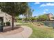 Beautifully landscaped walking path alongside a lake with lush green grass and mature trees at 1727 E Chelsea Ln, Gilbert, AZ 85295