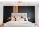 Stylish main bedroom featuring modern lighting fixture, black accent wall with wood slats, and cozy textiles at 1831 E Cornell Dr, Tempe, AZ 85283