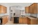 Spacious kitchen with oak cabinets, black appliances, tile floors and a view of the living room at 2191 W Goldmine Mountain Dr, Queen Creek, AZ 85144