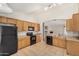Bright kitchen featuring oak cabinets, black appliances, tile floors, and a view of the living room at 2191 W Goldmine Mountain Dr, Queen Creek, AZ 85144