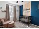 Bedroom with a blue accent wall, crib, chair, and ample natural light at 25119 N 134Th Dr, Peoria, AZ 85383