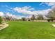 Expansive community green space with well-maintained lawn and mature trees under a bright blue sky with fluffy clouds at 3139 E Runaway Bay Pl, Chandler, AZ 85249