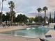 Expansive community pool surrounded by palm trees and comfortable seating, offering a resort-like experience at 3301 S Goldfield Rd # 6050, Apache Junction, AZ 85119