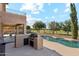 Well-equipped outdoor kitchen and grill area adjoins a sparkling pool with patio seating, perfect for outdoor dining at 3574 E Latham Way, Gilbert, AZ 85297