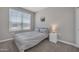 Neutral bedroom with a bed, nightstand, carpet, and large window providing plenty of natural light at 38150 W San Sisto Ave, Maricopa, AZ 85138