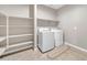 Well-lit laundry room featuring a washer and dryer and ample shelving space for organization at 38150 W San Sisto Ave, Maricopa, AZ 85138
