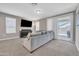 Bright living room with carpet, gray sofa, and sliding glass doors to outdoor space at 38150 W San Sisto Ave, Maricopa, AZ 85138