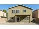 Back exterior of the house featuring a covered patio, desert landscaping, and multiple windows at 409 E Saddle Way, San Tan Valley, AZ 85143