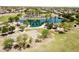 Expansive aerial shot of community park featuring a lake, playground, and basketball court at 44236 W Adobe Cir, Maricopa, AZ 85139
