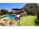 An oasis of relaxation featuring a sparkling pool, lush greenery, and putting green at 44236 W Adobe Cir, Maricopa, AZ 85139