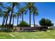Stone monument sign under palm trees marking the entrance to Cobblestone Farms community at 44236 W Adobe Cir, Maricopa, AZ 85139