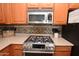 A stainless steel range and microwave are centered in this cozy kitchen with light countertops and wood cabinets at 44236 W Adobe Cir, Maricopa, AZ 85139