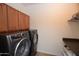 Practical laundry room with stainless steel washer and dryer and overhead storage at 44236 W Adobe Cir, Maricopa, AZ 85139