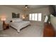 A main bedroom with a ceiling fan, plantation shutters, carpeting, and contemporary decor at 44236 W Adobe Cir, Maricopa, AZ 85139