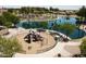 Scenic view of a vibrant community playground beside a lake lined with palm trees at 44236 W Adobe Cir, Maricopa, AZ 85139
