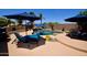 Backyard pool with waterfall feature, a built-in barbeque, and blue patio umbrellas at 44236 W Adobe Cir, Maricopa, AZ 85139