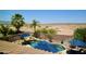Backyard pool area with lush palm trees, rock waterfall feature, and views of the surrounding desert at 44236 W Adobe Cir, Maricopa, AZ 85139