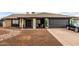 Charming single-story home with a black two-car garage and desert rock landscaping at 4441 W Windrose Dr, Glendale, AZ 85304