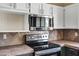 Close-up of kitchen appliances, featuring a stainless steel oven and microwave with marble tile backsplash at 4449 E Rancho Caliente Dr, Cave Creek, AZ 85331
