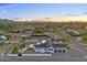 Expansive aerial view of a modern home with a pool, black roof, and a beautiful desert sunset at 6147 E Desert Cove Ave, Scottsdale, AZ 85254