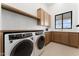 Well-equipped laundry room with modern washer/dryer and custom cabinets with stone countertops at 6147 E Desert Cove Ave, Scottsdale, AZ 85254