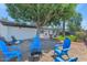 Backyard with blue chairs, fire pit, and a mature tree providing shade, surrounded by lush greenery at 6207 E Rose Circle Dr, Scottsdale, AZ 85251