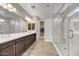 Spacious bathroom featuring a double sink, tiled floors, a glass-enclosed shower, and a walk-in closet at 6503 E Bluefield Ave, Phoenix, AZ 85054