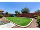 Well-manicured backyard featuring lush synthetic grass, decorative elements, and inviting seating at 7015 W Melody Dr, Laveen, AZ 85339
