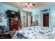 A bright bedroom with blue walls, floral bedding, two dressers, a sliding glass door and a view of the ensuite at 7015 W Melody Dr, Laveen, AZ 85339