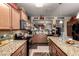 A full kitchen with granite countertops, stainless steel appliances, wood cabinets, and a view to the dining room at 7015 W Melody Dr, Laveen, AZ 85339