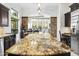 Bright kitchen featuring a large granite island, stainless steel appliances, and custom dark wood cabinetry at 8433 E Leonora St, Mesa, AZ 85207