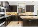 A modern kitchen features dark wood cabinets, stainless steel appliances, and ample counter space with a granite island at 8433 E Leonora St, Mesa, AZ 85207