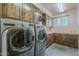 Practical laundry room with wood cabinetry, modern washer and dryer, and ample countertop space at 8606 E Arroyo Seco Rd, Scottsdale, AZ 85266