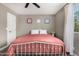 A cozy bedroom with a ceiling fan, light gray walls, a bed with a pink cover, and natural light at 8829 W Sheridan St, Phoenix, AZ 85037