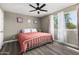 A cozy bedroom with a ceiling fan, light gray walls, a bed with a pink cover, and natural light at 8829 W Sheridan St, Phoenix, AZ 85037