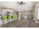Bright living room with a ceiling fan, modern lighting, and stairs leading up, flowing into the open kitchen at 8829 W Sheridan St, Phoenix, AZ 85037