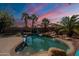 Backyard pool with rock features, palm trees, and string lights, perfect for outdoor entertaining at 11526 W Bermuda Dr, Avondale, AZ 85392