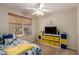 Bright bedroom with a ceiling fan and window, with a dresser with blue and yellow accents at 11543 W Sandsnake Ct, Surprise, AZ 85378