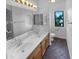 Bathroom with dual sinks, vanity, tile flooring, and a wall-mounted mirror at 13335 W Marlette Ct, Litchfield Park, AZ 85340