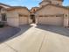 A home featuring a beige garage with two doors, complemented by a paved driveway leading to the residence at 13335 W Marlette Ct, Litchfield Park, AZ 85340
