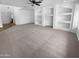 Open-concept living room with built-in shelving and neutral carpeting at 13335 W Marlette Ct, Litchfield Park, AZ 85340