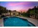 Picturesque backyard highlighting a pristine pool reflecting the vibrant sunset sky, surrounded by desert plants and a well-maintained lawn at 14717 N 97Th Pl, Scottsdale, AZ 85260