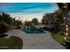 Stunning backyard oasis showcasing a serene pool with a water feature, surrounded by lush landscaping and ambient lighting at 14717 N 97Th Pl, Scottsdale, AZ 85260