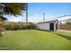 Backyard featuring green turf, mature trees, and detached garage at 1615 E Roma Ave, Phoenix, AZ 85016