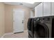 Bright laundry room features a white door, tile flooring, and efficient gray washer and dryer, plus plenty of storage space at 1621 W Wildwood Dr, Phoenix, AZ 85045