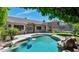 An inviting pool sits on the back patio surrounded by lush green yard, stone and green shrubbery at 1621 W Wildwood Dr, Phoenix, AZ 85045