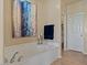 Bright bathroom featuring a large soaking tub, stylish decor, and a doorway to the water closet at 16420 N Thompson Peak Pkwy # 1002, Scottsdale, AZ 85260