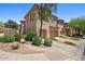 A tan townhome featuring a three-car garage, desert landscaping, and stone accents at 16420 N Thompson Peak Pkwy # 1002, Scottsdale, AZ 85260