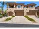 Beige townhome showcasing a three-car garage and lovely desert landscaping at 16420 N Thompson Peak Pkwy # 1002, Scottsdale, AZ 85260